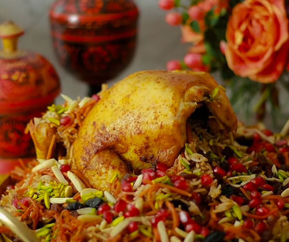 Gefülltes Hähnchen auf aromatischem Gewürzreis mit Nüssen und Granatapfel, afghanisches Festgericht